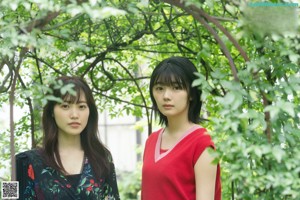 A couple of women standing on top of a lush green field.