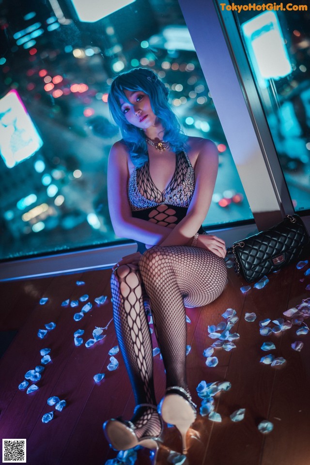 A woman sitting on the floor in fishnet stockings.