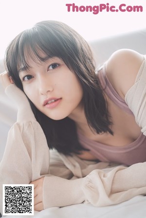 A woman sitting on the floor in front of a white brick wall.