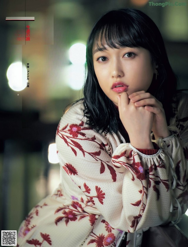 A woman in a kimono sitting on a chair with her hand on her chin.