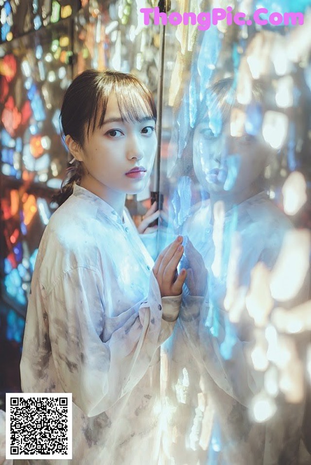 A woman standing in front of a mirror in a room.