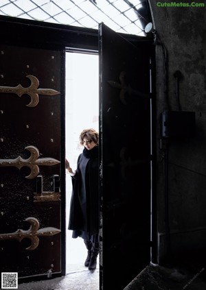 A woman in a black coat and gloves standing in the snow.