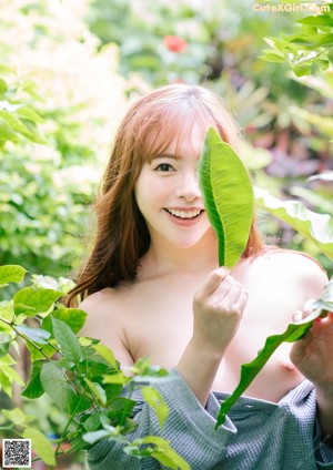 A naked woman sitting on a red chair in the woods.