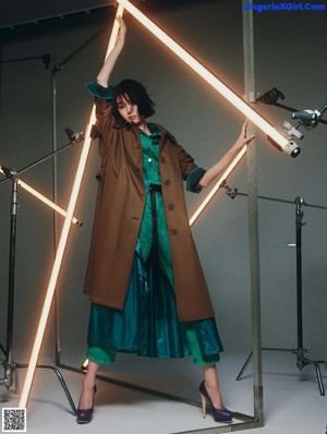 A woman in a black dress and coat standing in front of a light.