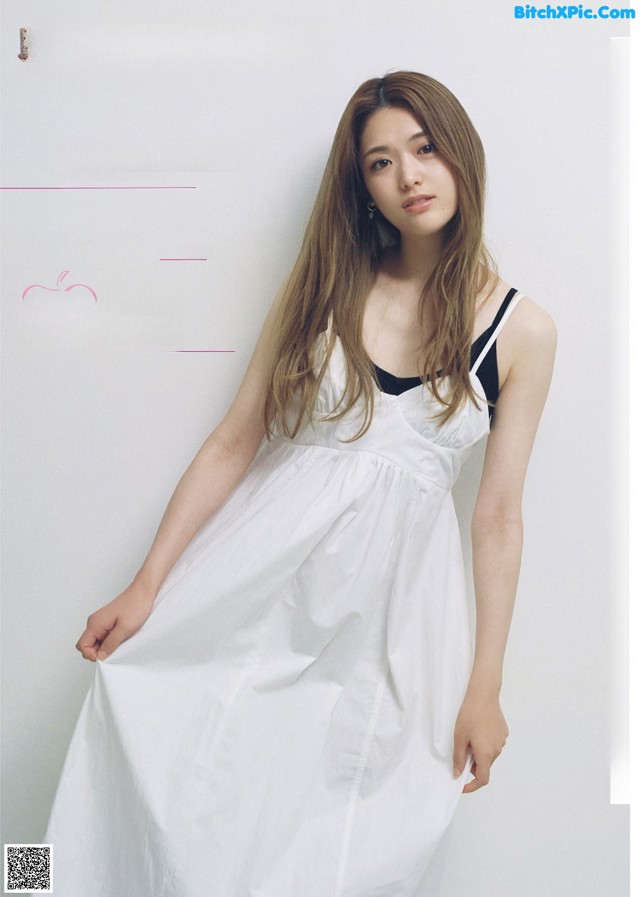 A woman in a white dress is posing for a magazine.