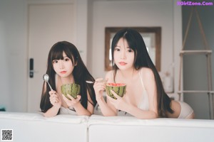 A couple of women sitting next to each other on a window sill.