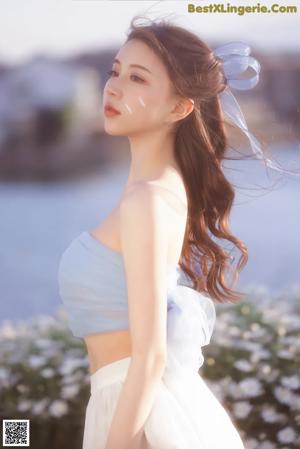 A woman in a white dress holding a flower in her hand.
